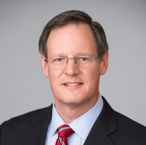 Professional headshot with glasses and red tie